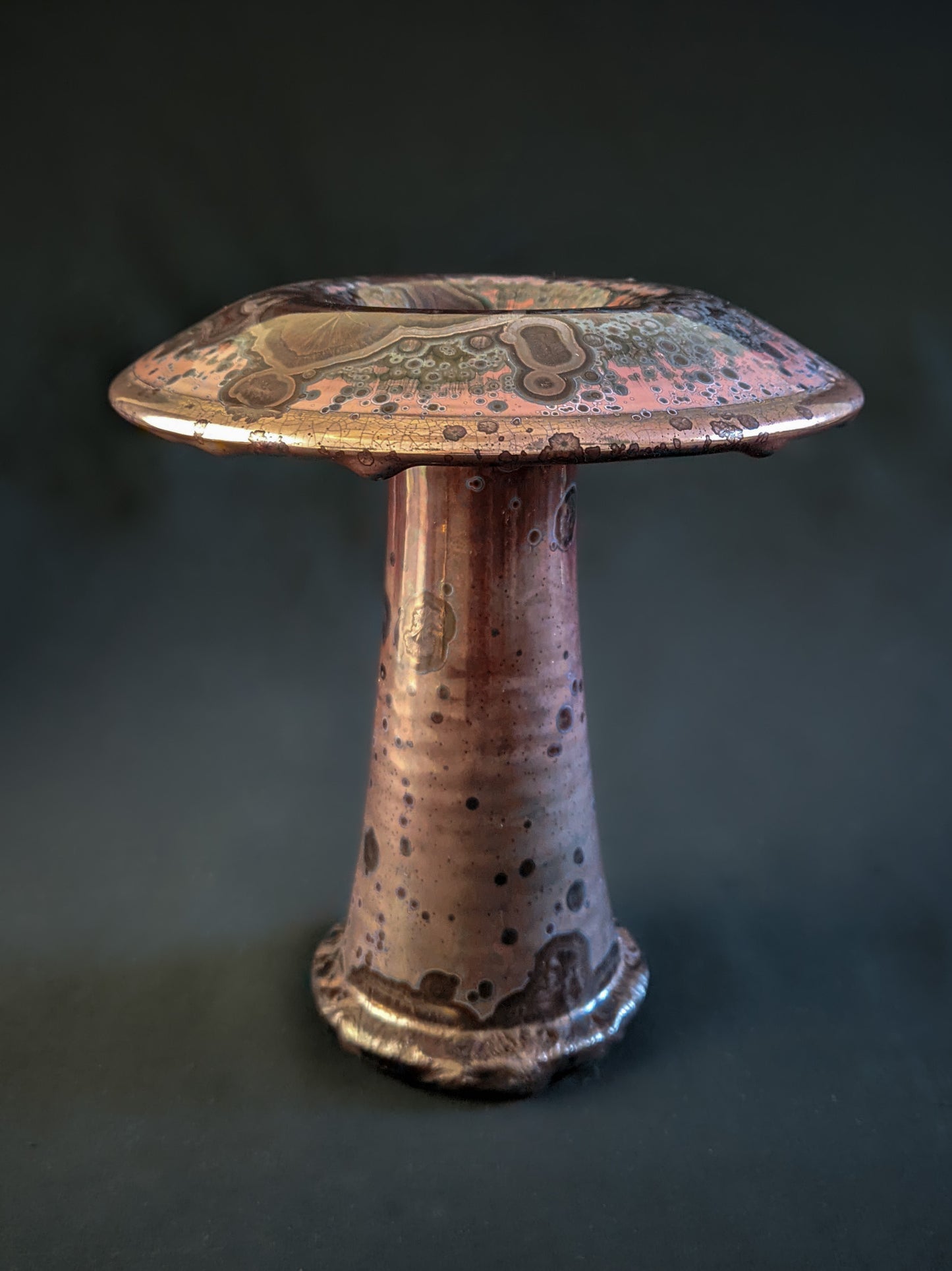 Red ceramic mushroom vase with golden crystals and a shiny rim, created using a reduction firing technique, with a tall, slender shape.