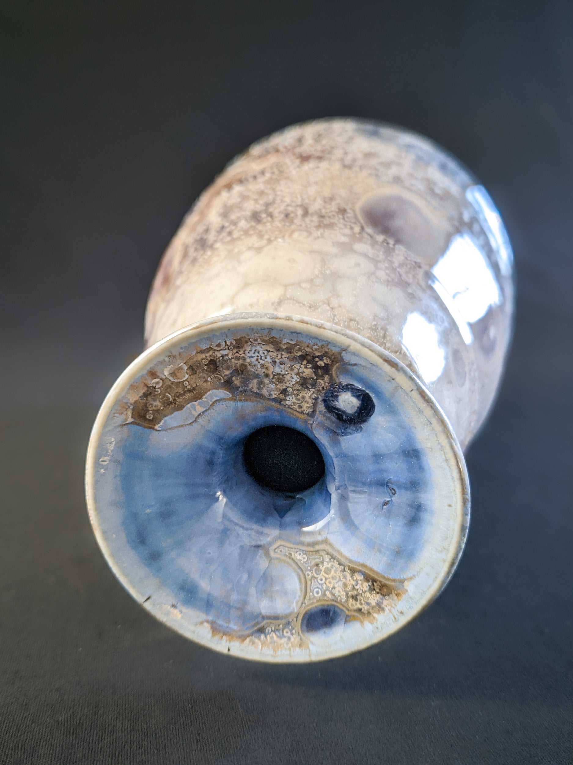 Close-up of the vase's lip, showcasing delicate bursts of light blue crystalline formations emerging through the molten glaze, creating a striking contrast with the surrounding earthy tones.