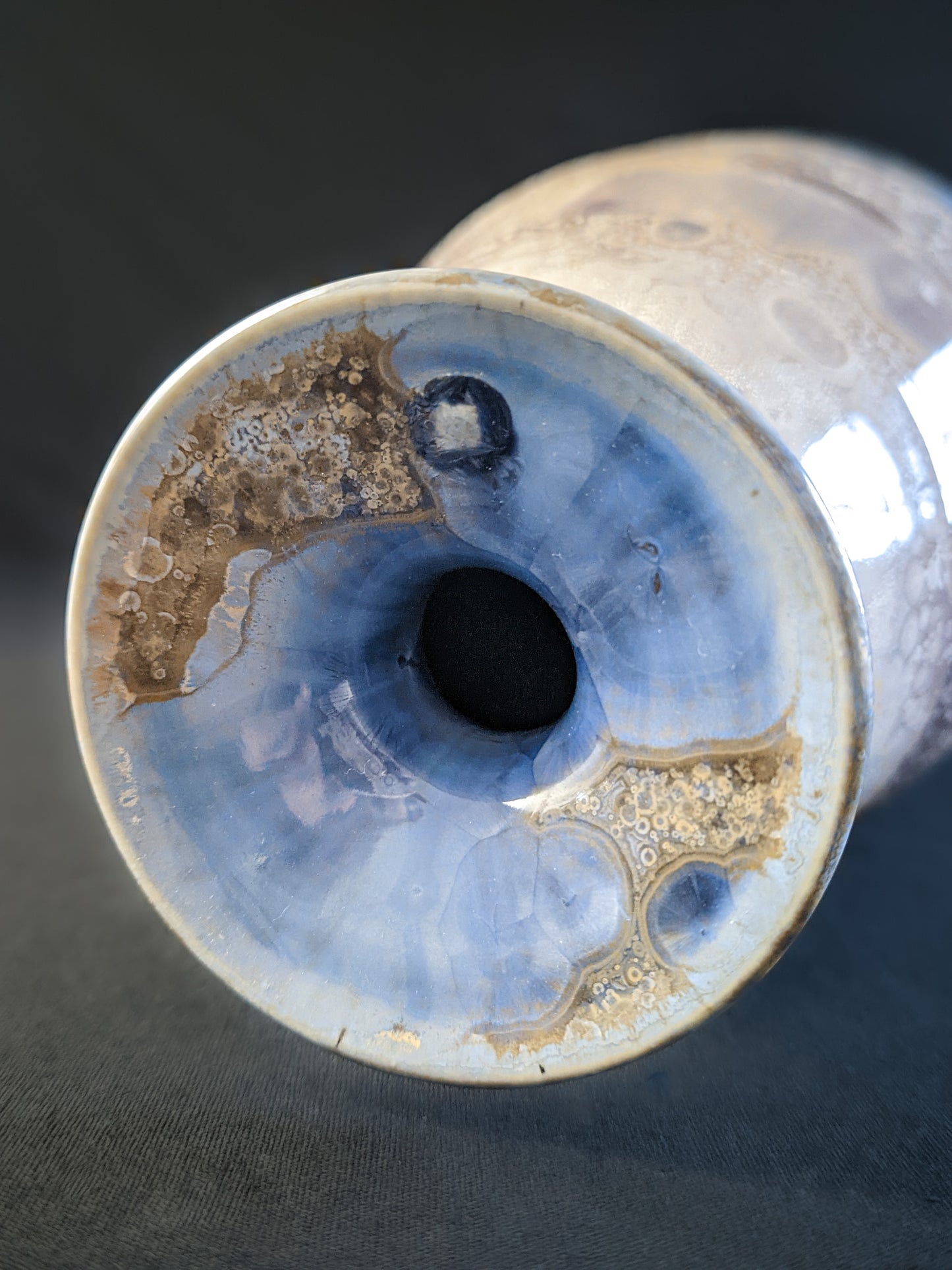 Close-up of the vase's lip, showcasing delicate bursts of light blue crystalline formations emerging through the molten glaze, creating a striking contrast with the surrounding earthy tones.