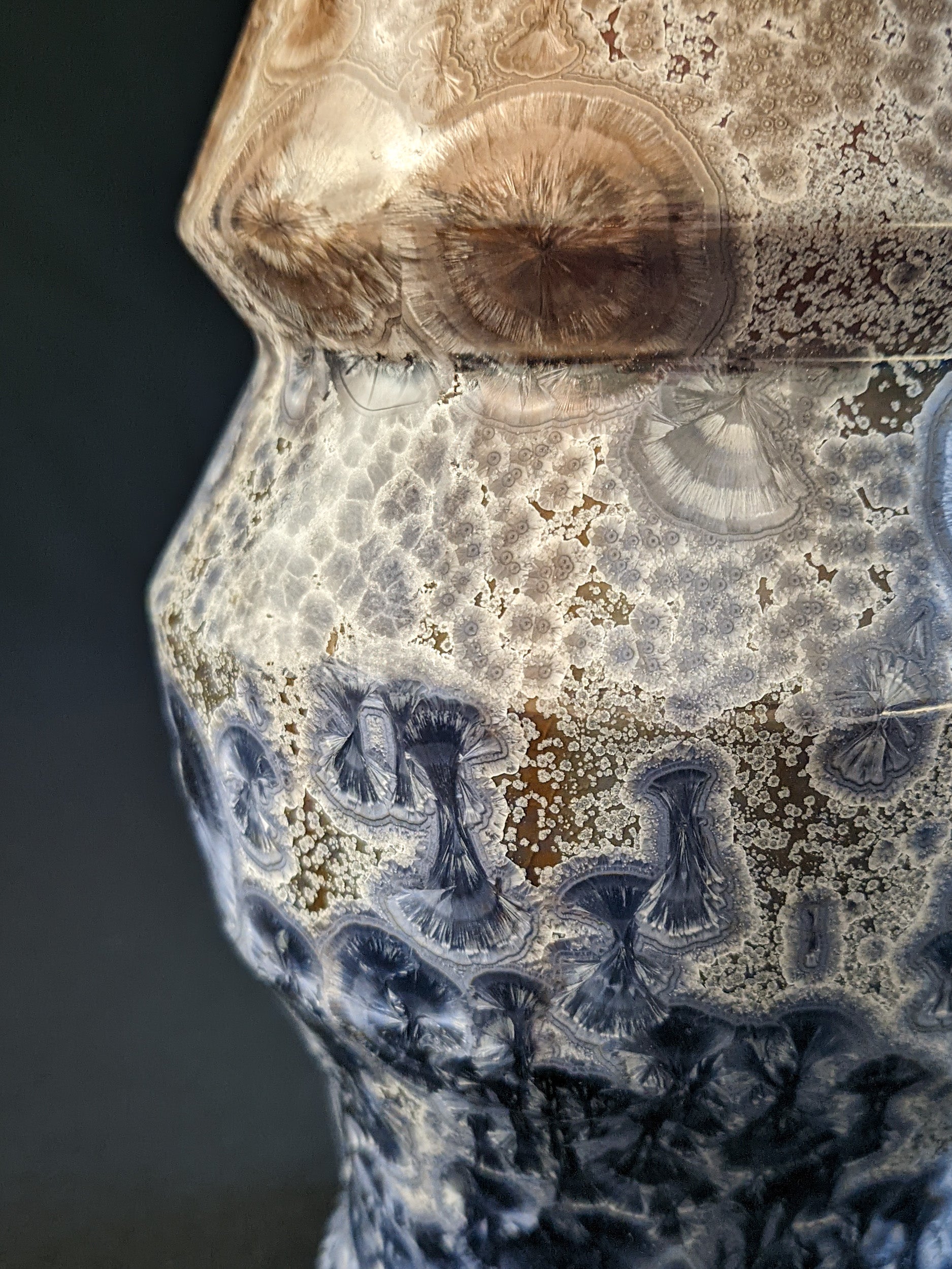 Close-up of the vase's side, featuring a mushroom-themed background with a gradient of crystals: large blue crystals near the bottom, small grey crystals in the middle, and larger brown crystals near the top, highlighting the intricate texture and color transitions.