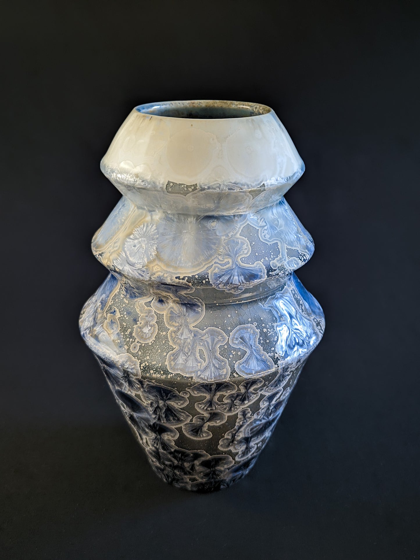 Frozen Serenity vase, showcasing its angular silhouette and captivating blend of deep blue and soft ivory hues, with glimmering crystalline patterns adding depth and movement.