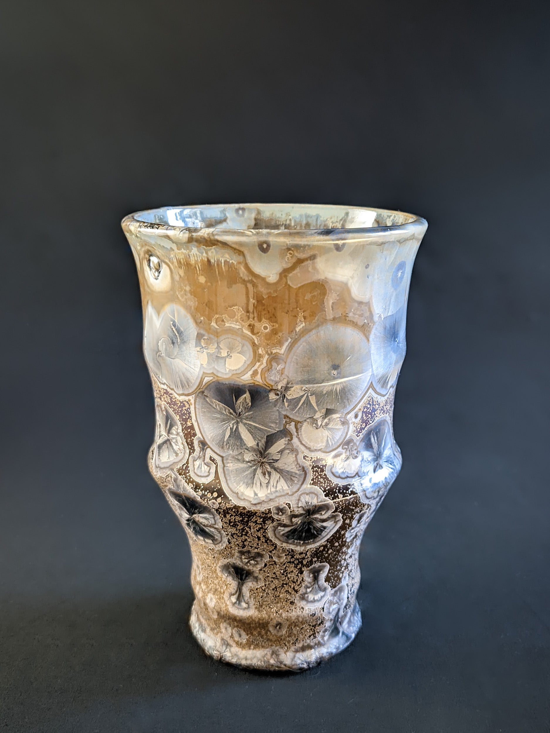A sculptural vase with a warm brown background, with icy blue crystalline glaze.