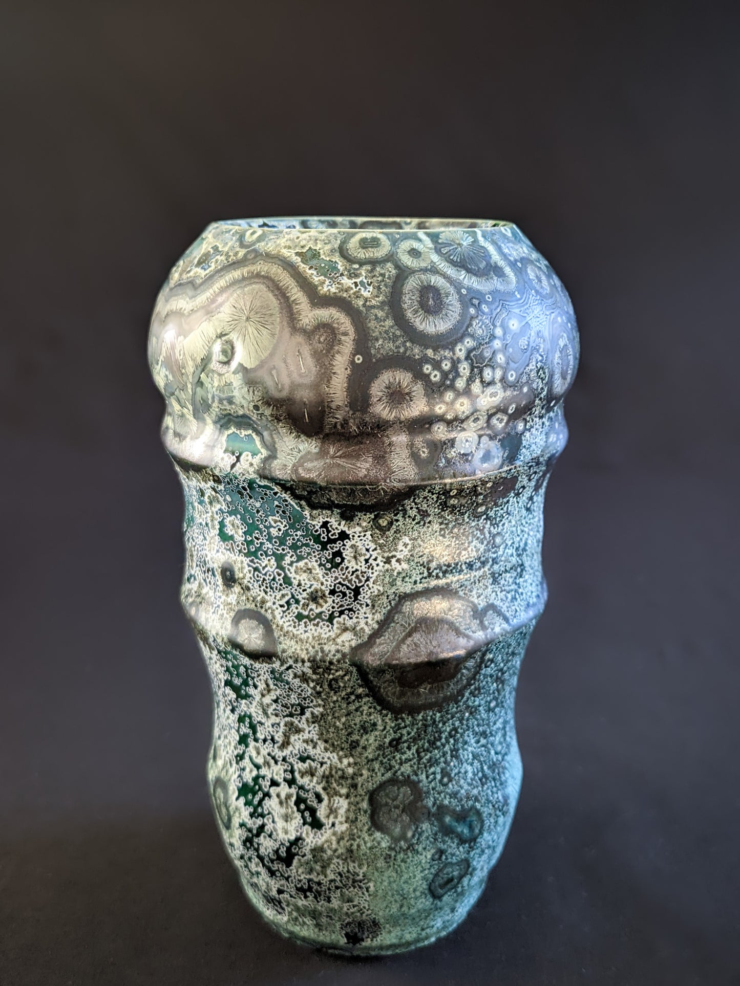 Emerald green crystalline-glazed vase with large nickel and gold-toned crystals, each framed by white rings. 