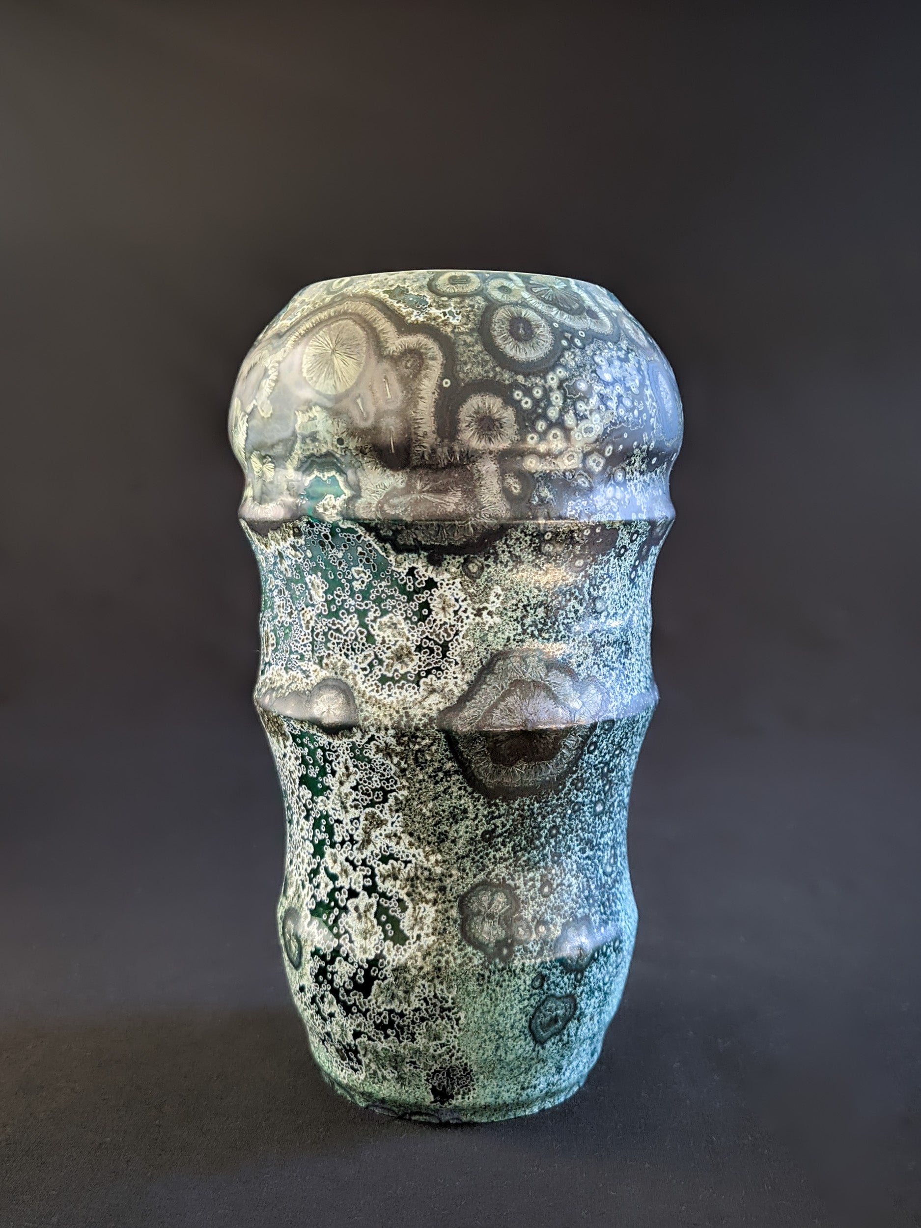 Green crystalline sculptural vase with elegant curves.