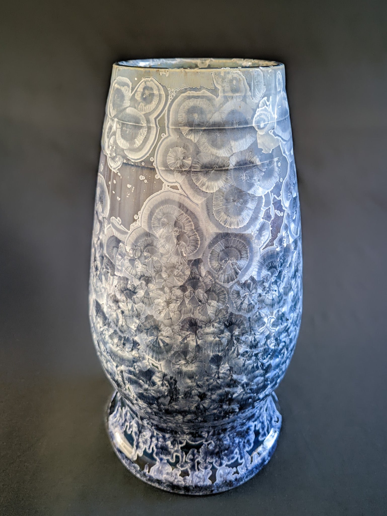 Large, sculptural vase with a wide opening, showcasing a dramatic color gradient from dark blue to light purple and white. The vase is adorned with overcrystallized blue crystals with white rings, creating an artistic texture.