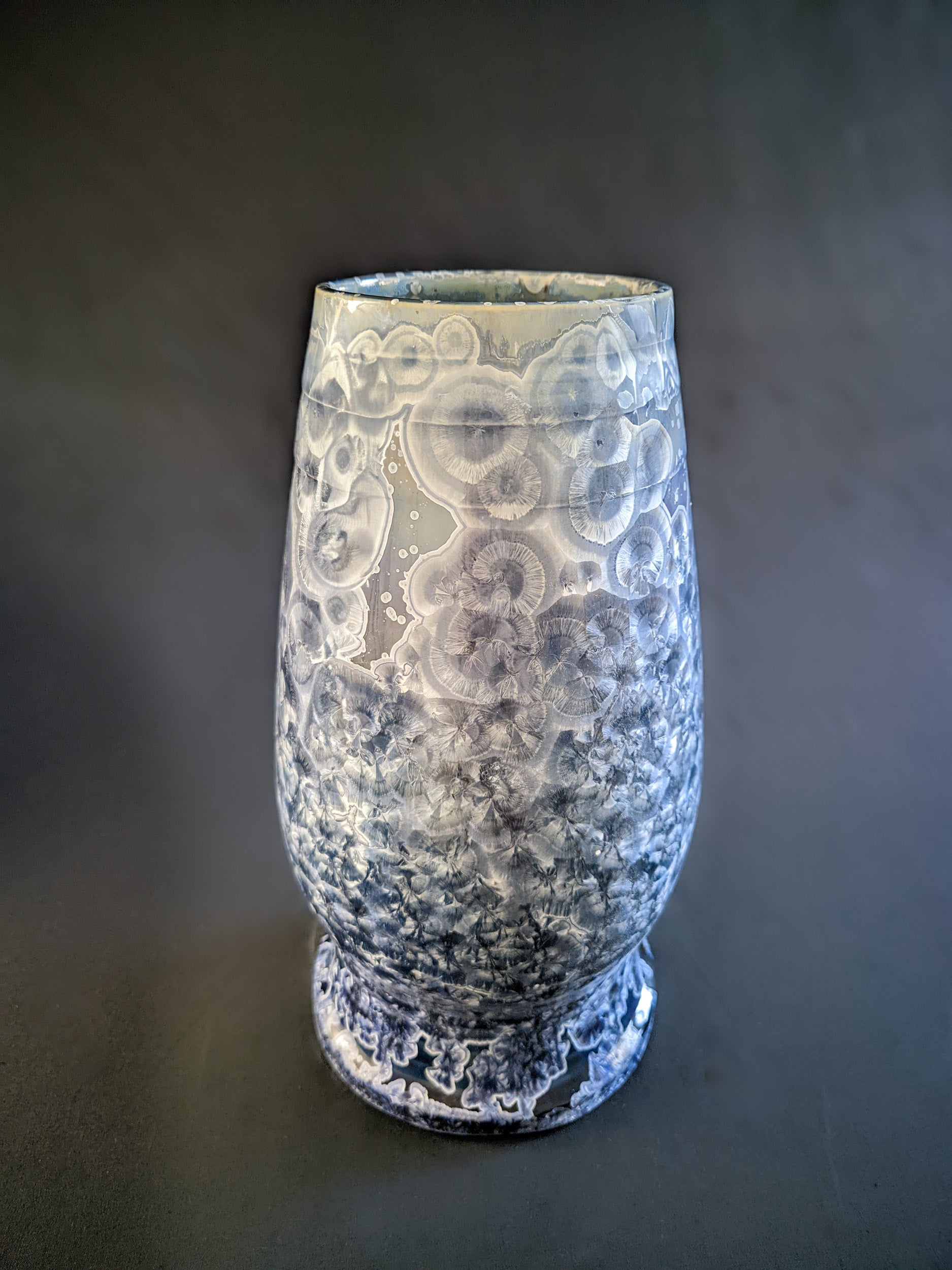 Large, sculptural vase with a wide opening, showcasing a dramatic color gradient from dark blue to light purple and white. The vase is adorned with overcrystallized blue crystals with white rings, creating an artistic texture.