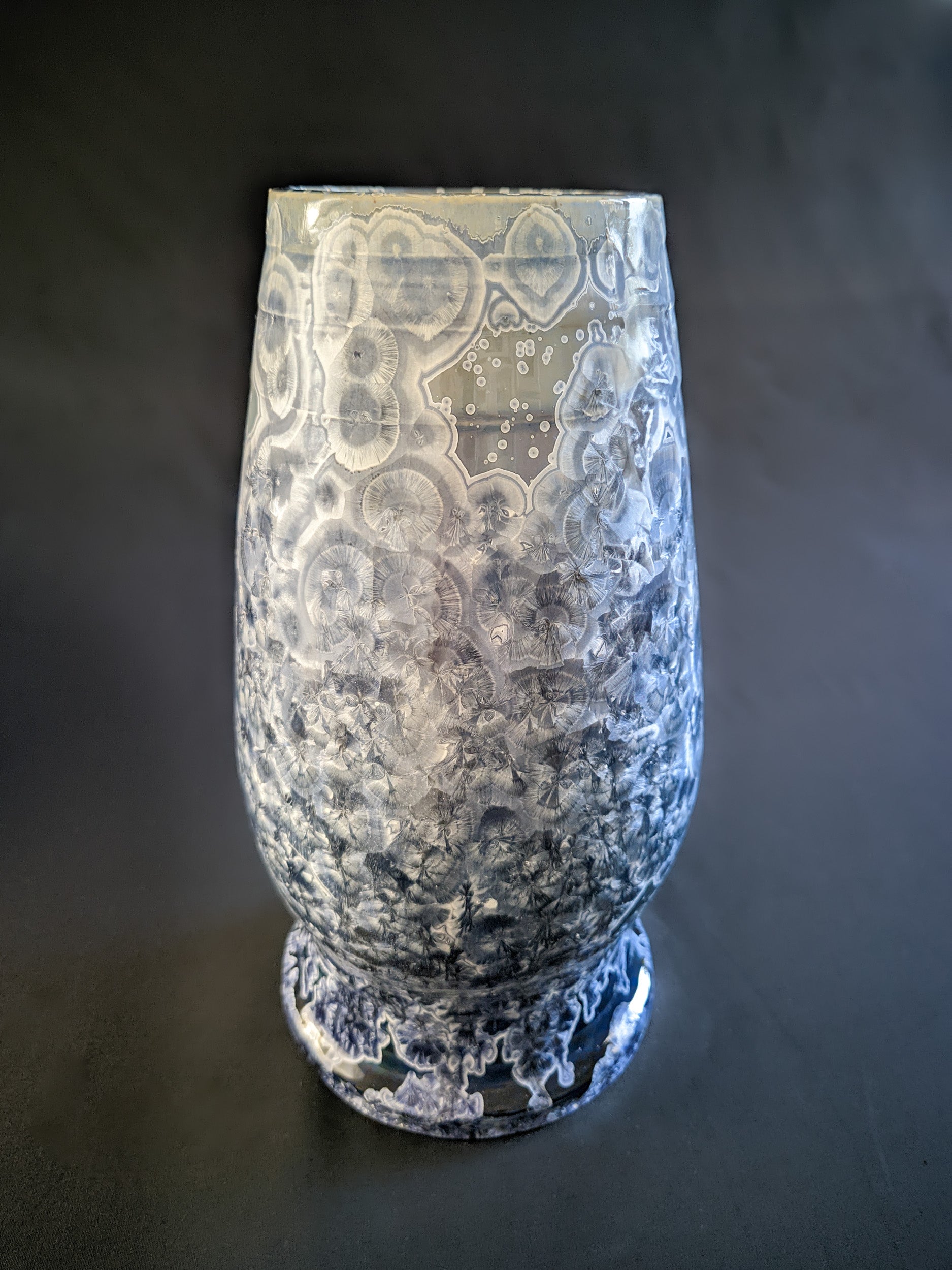 Large, sculptural vase with a wide opening, showcasing a dramatic color gradient from dark blue to light purple and white. The vase is adorned with overcrystallized blue crystals with white rings, creating an artistic texture.
