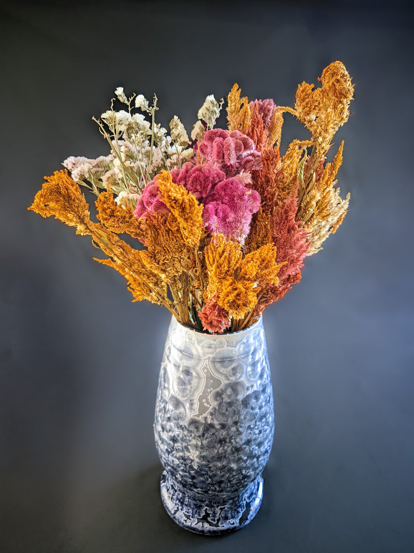 Large, sculptural vase with a wide opening, showcasing a dramatic color gradient from dark blue to light purple and white. The vase is adorned with overcrystallized blue crystals with white rings, creating an artistic texture. A large bouquet of dried wildflowers fills the vase, showcasing its size and ability to hold stunning floral arrangements.