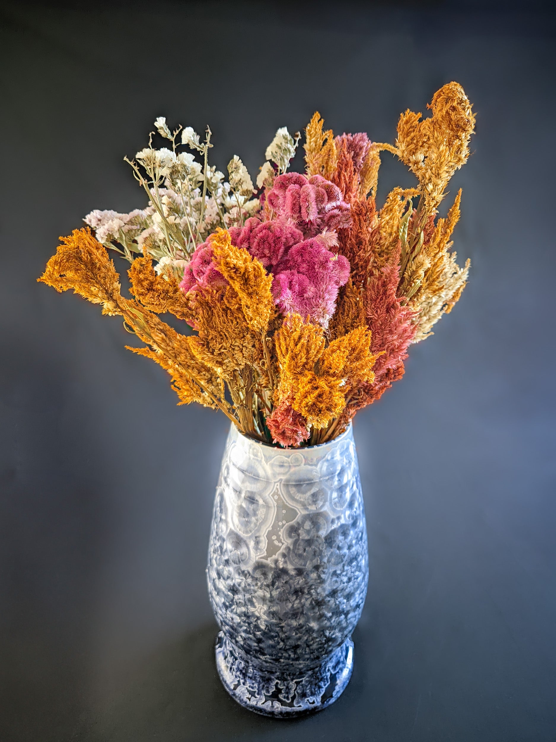 Large, sculptural vase with a wide opening, showcasing a dramatic color gradient from dark blue to light purple and white. The vase is adorned with overcrystallized blue crystals with white rings, creating an artistic texture. A large bouquet of dried wildflowers fills the vase, showcasing its size and ability to hold stunning floral arrangements.