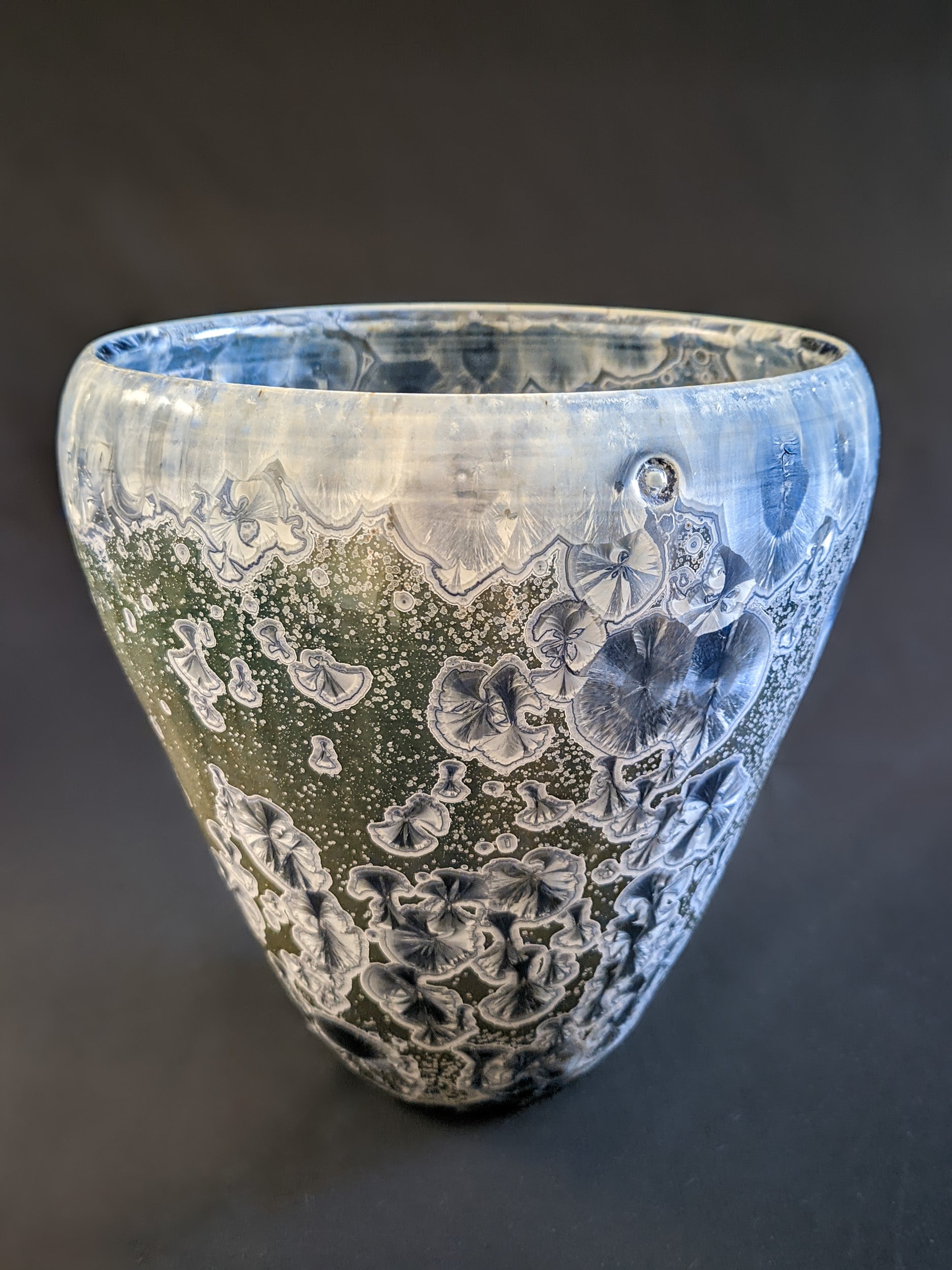 A wide, conical sculptural vessel with a muted green background and large blue crystalline formations, transitioning from deep sapphire to icy blue near the rim.