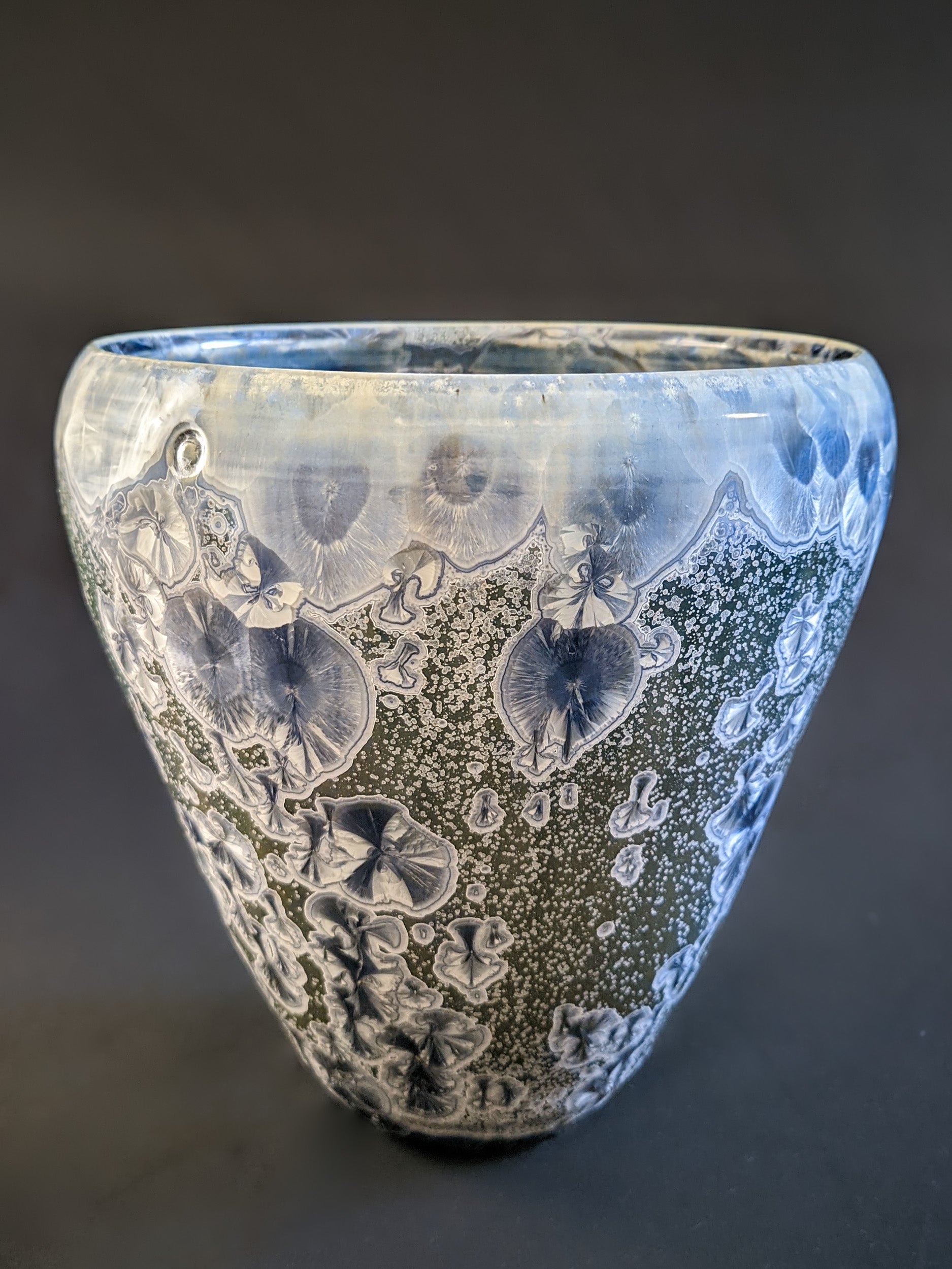 A conical vessel with a muted green background and large icy blue crystalline formations.