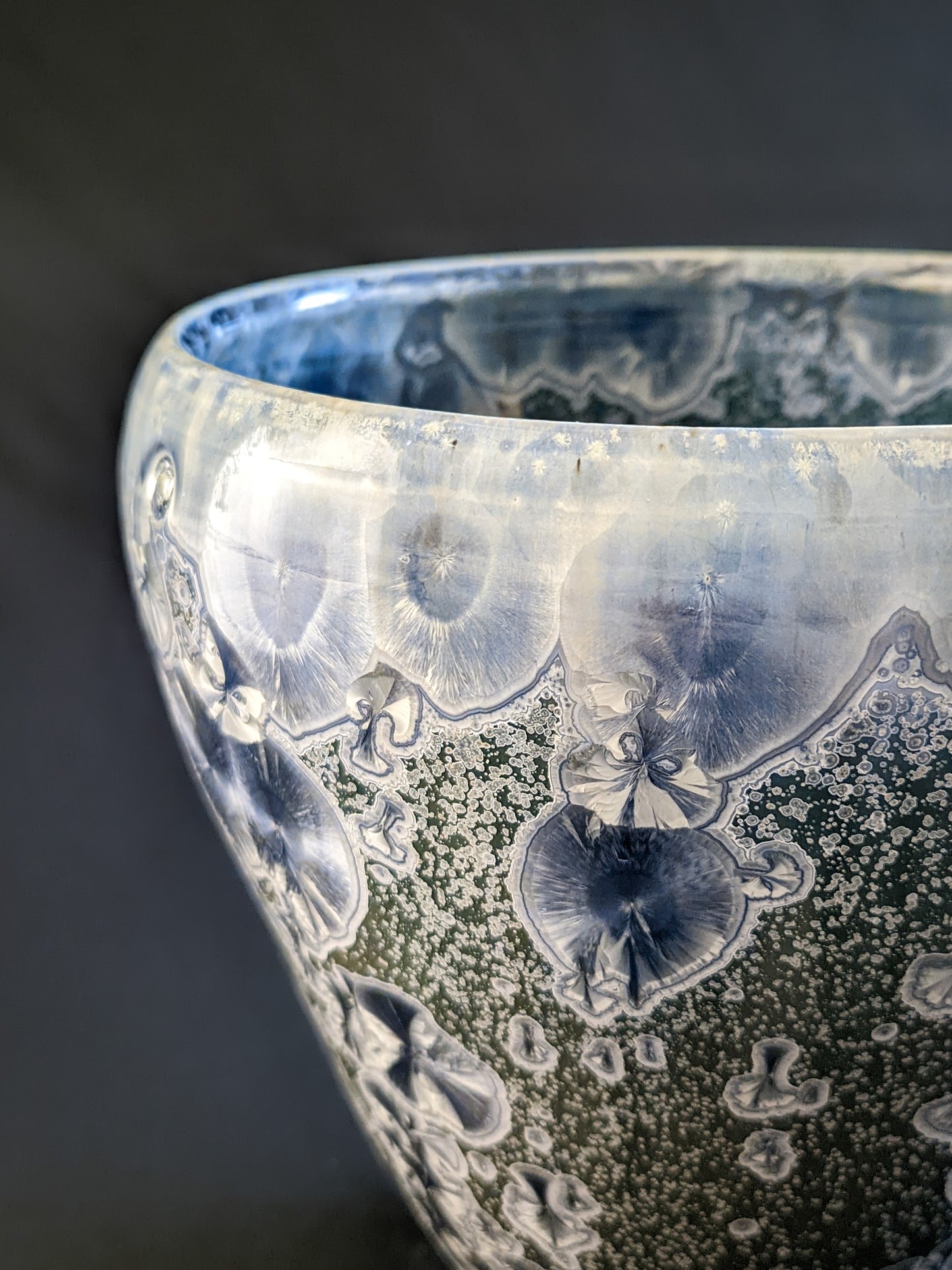 The vessel’s rim, showcasing a soft gradient from green to icy blue, with intricate crystalline formations and a lightly textured surface.