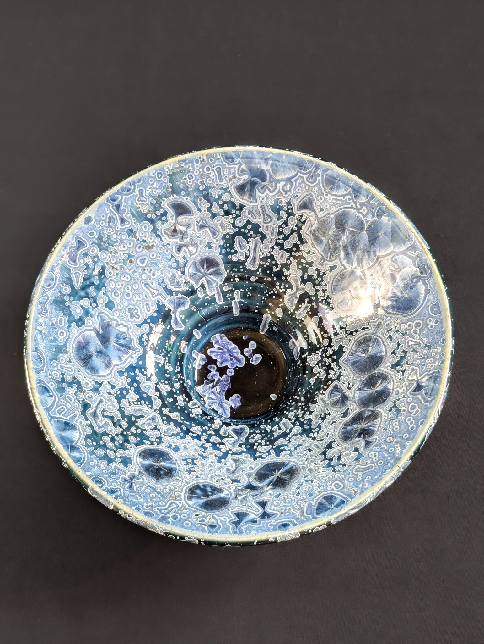 Top view of porcelain trinket dish by Robbin Harris featuring sapphire colored crystals on a navy background.